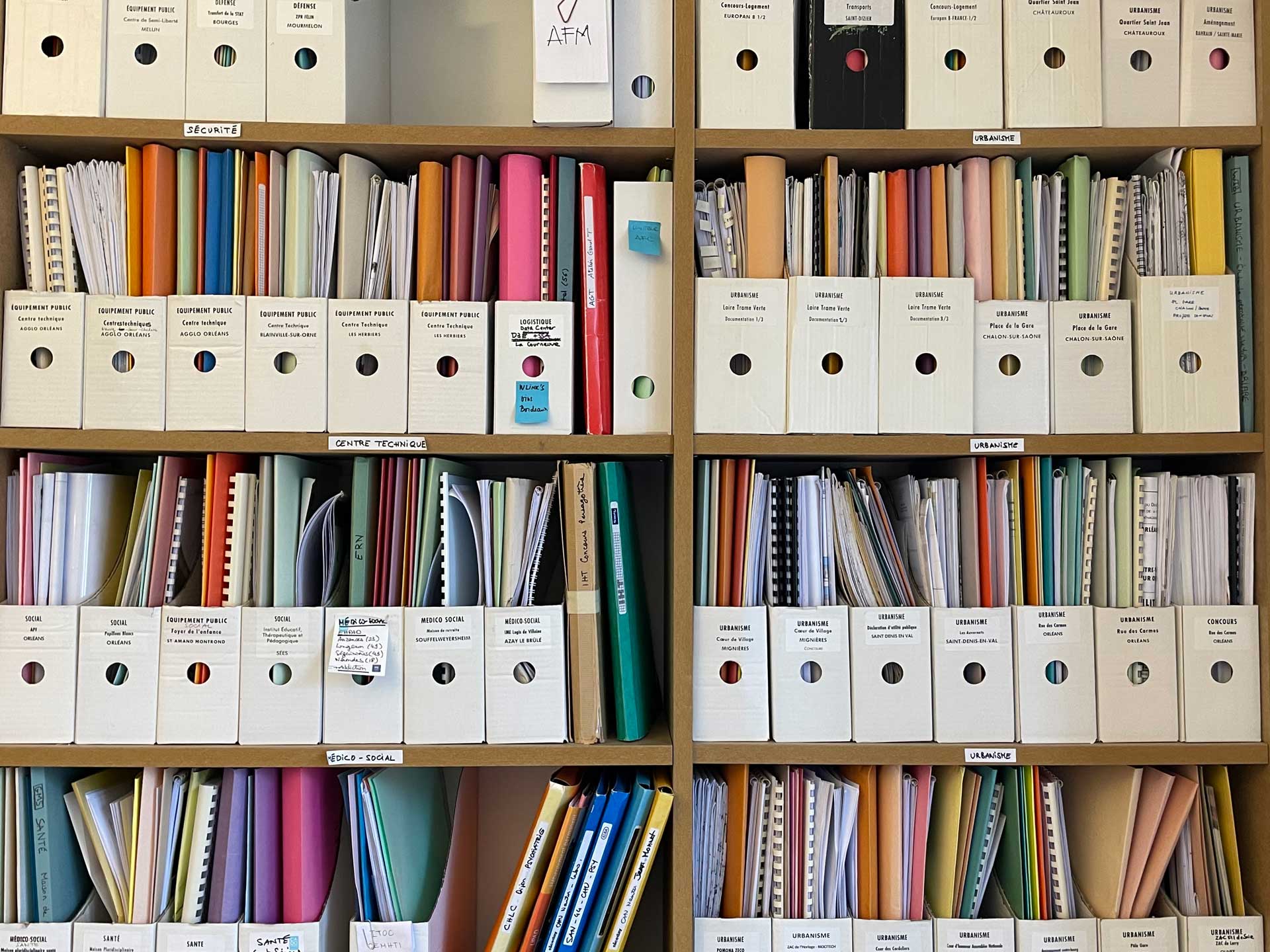 Photo de bibliothèque de dossier dans une agence d'architecture. Dossiers multicolores et rangé dans des boites
